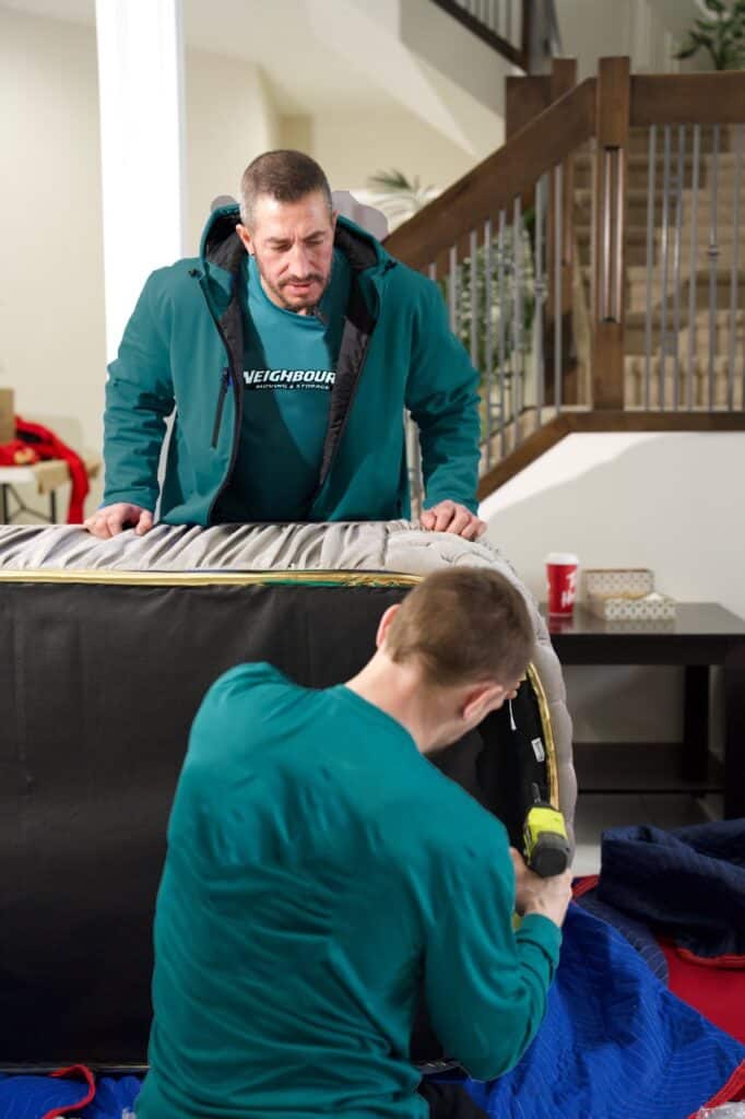 Moving professionals carefully lifting furniture during a residential move in a home.