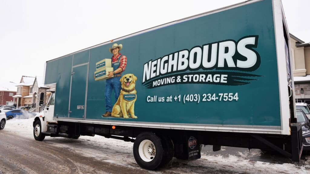 Reliable Neighbours Moving & Storage truck with a friendly mover and dog in a snowy neighborhood.