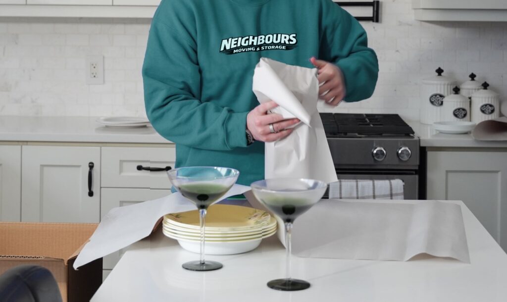 Neighbours Moving & Storage professional carefully wraps fragile kitchenware and glassware using protective packing paper to keep valuables safe and secure during moving and storage services