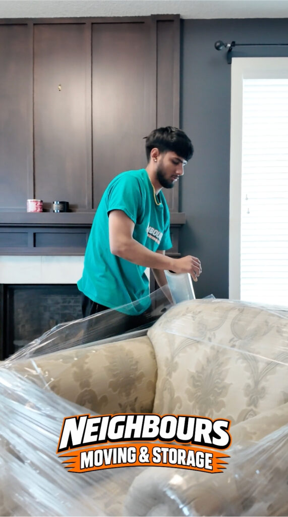 Professional mover wraps a sofa with stretch film to protect it from dust, scratches, and damage during a safe residential move.