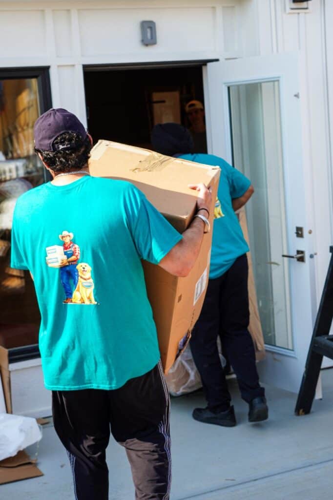 Movers carrying a large box into a house during a relocation process.