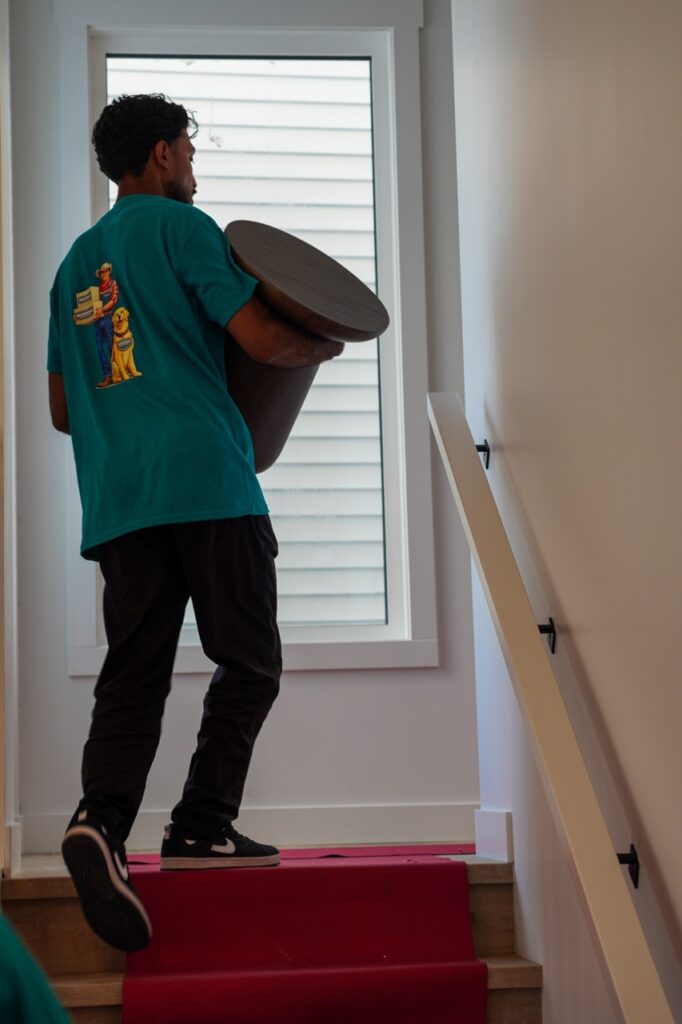 Aurora movers carrying a table upstairs with floor protection during a home move